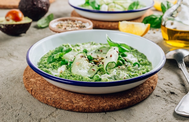 Cold green soup Gazpacho with cucumber, green peas, basil leaves, and avocado