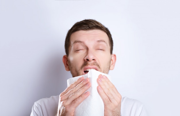 Cold guy sneezes into a napkin