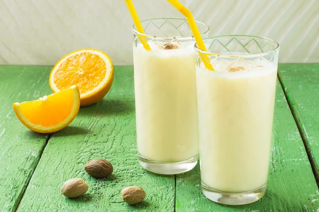 Cold homemade milkshake with ice cream orange juice and nutmeg