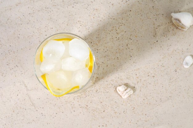 Foto ghiaccio freddo in un bicchiere d'acqua sulla sabbia summer drink concept