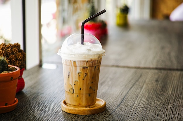 Cold Iced Coffee in plastic glass on table in the coffee cafe