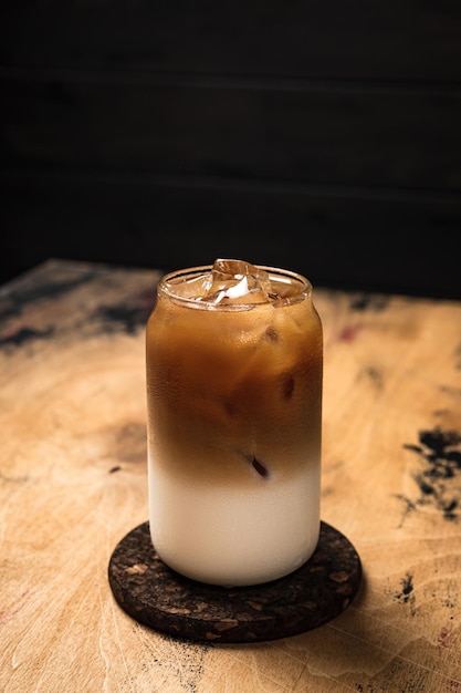 Caffè freddo freddo al latte un bicchiere highball alto riempito con una bevanda rinfrescante a strati di cubetti di ghiaccio