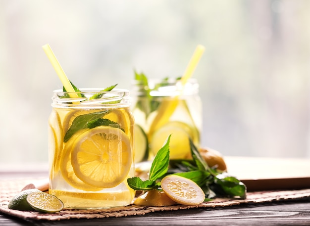 Cold lemonade from lemon and lime in glass jars with straws