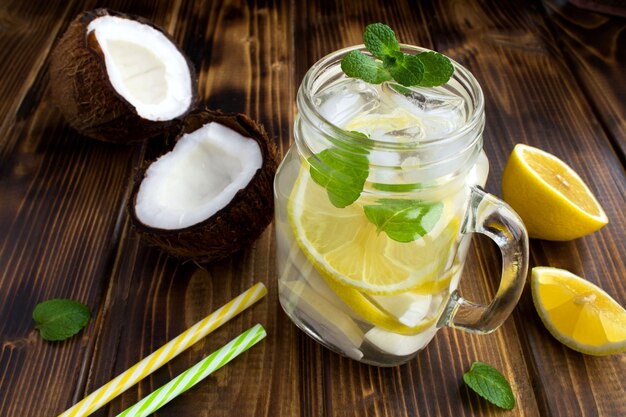 Cold lemonade with coconut,lemon and mint on the brown wooden background