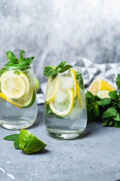 Cold lemonade with mint, lemon and lime in a glass. Preparation of lemonade