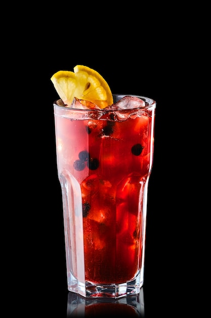 Cold lemonade with orange juice and black currant isolated on\
black background