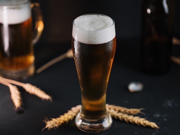 Cold light beer in a glass on a dark table