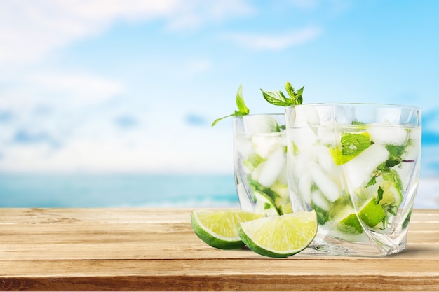 Bevanda fredda al mojito, bicchiere di alcol isolato su sfondo bianco, menta fresca e fetta di frutta lime,