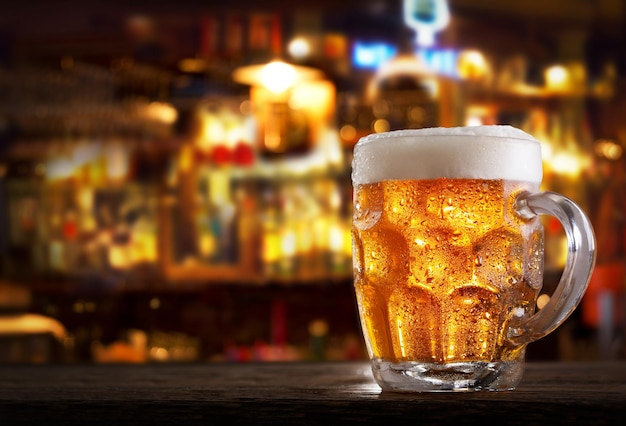 Cold mug of beer in a bar on wooden table