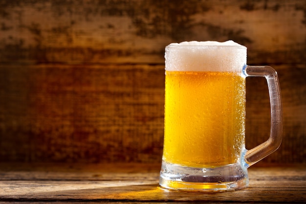 Cold mug of beer on wooden table