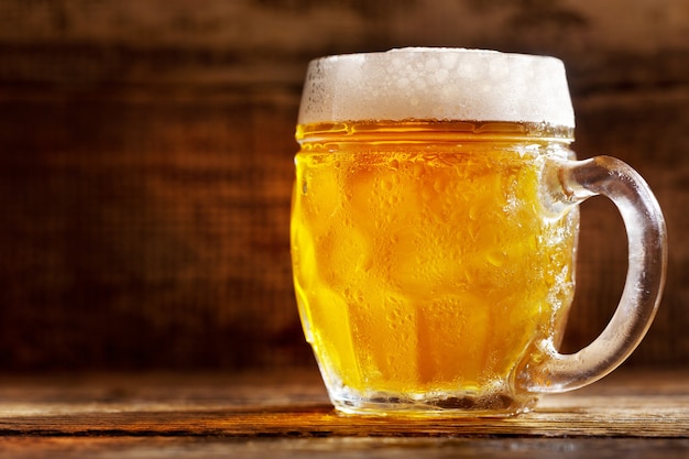 Cold mug of beer on wooden table