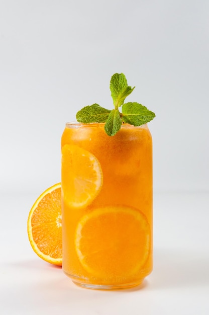 Холодный апельсиновый коктейль со льдом, украшенный листиком мяты