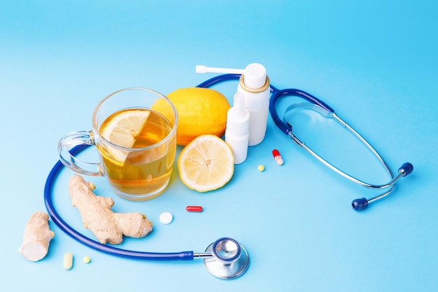 Холодные препараты стетоскоп чай лимон и корень имбиря на синем фоне