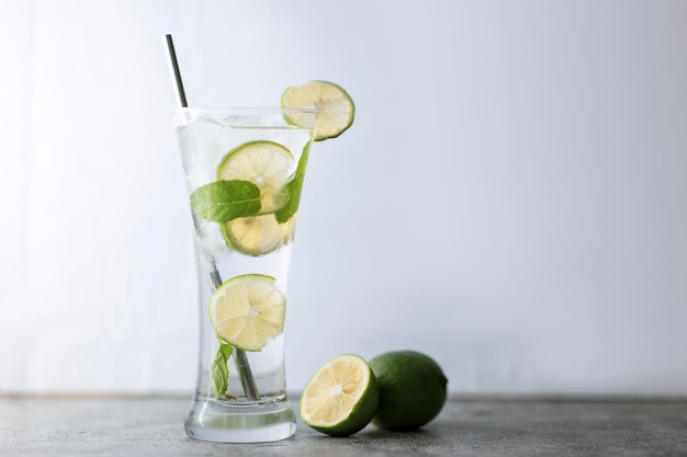 Cold refreshing beverage with sliced lime ripes and ice reverse light image in studio with white illuminated background and copy space