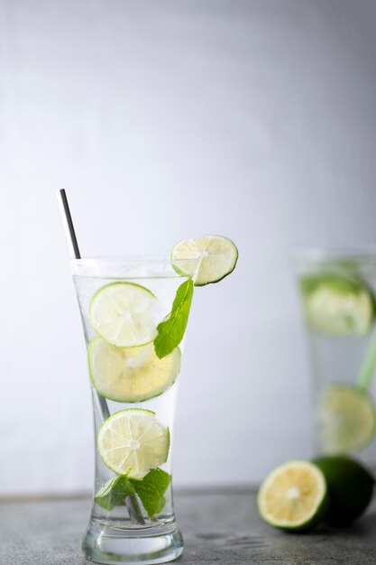 Cold refreshing beverage with sliced lime ripes and ice reverse light image in studio with white illuminated background