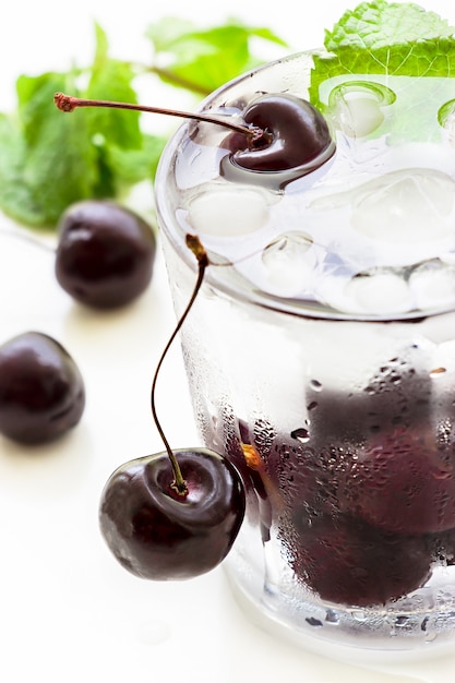 Cold refreshing detox water with cherry, mint and ice cube in glass. 