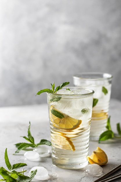Cold and refreshing detox water with lemon mint and ice in glasses Homemade lemonade or cocktail