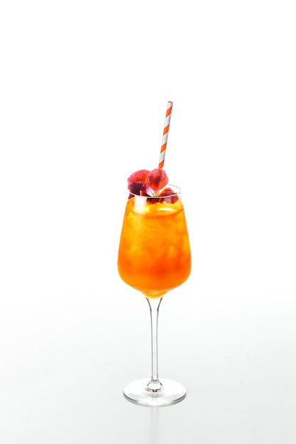 Cold and refreshing orange cocktail, ecorated with a living flower on top, served with a drinking straw, isolated