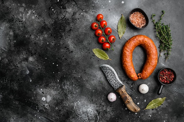 Cold smoked handmade sausage set, on black dark stone table background, top view flat lay, with copy space for text