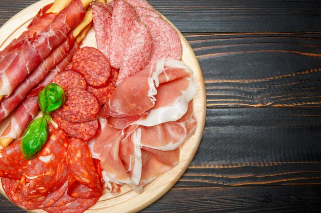 Cold smoked meat plate with pork chops, prosciutto, salami and bread sticks