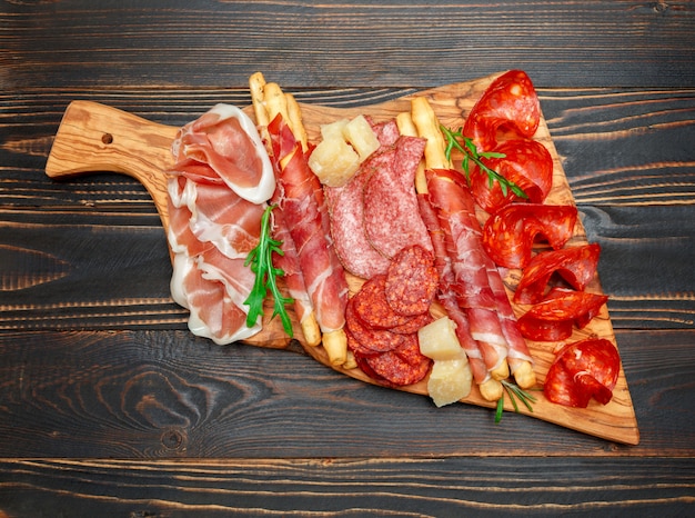 Cold smoked meat plate with pork chops, prosciutto, salami and bread sticks