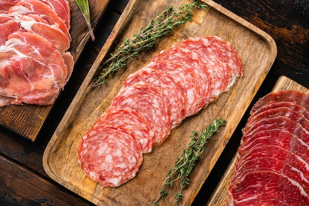 Cold smoked meat plate with prosciutto, salami, bacon set, on old dark  wooden table background, top view flat lay