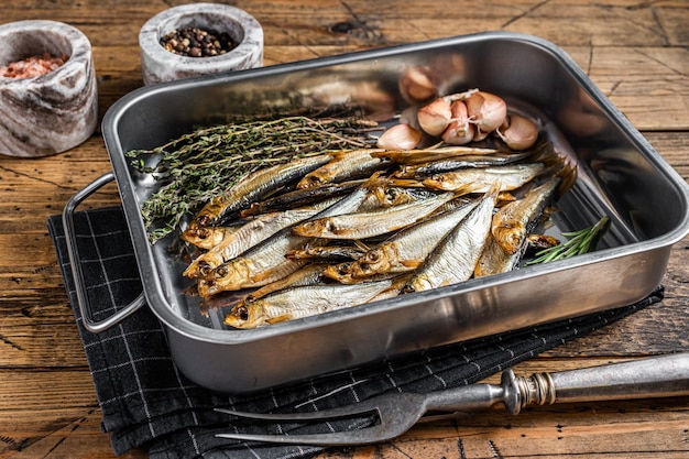 Pesce spratto affumicato a freddo in un vassoio da cucina con spezie sfondo in legno vista dall'alto