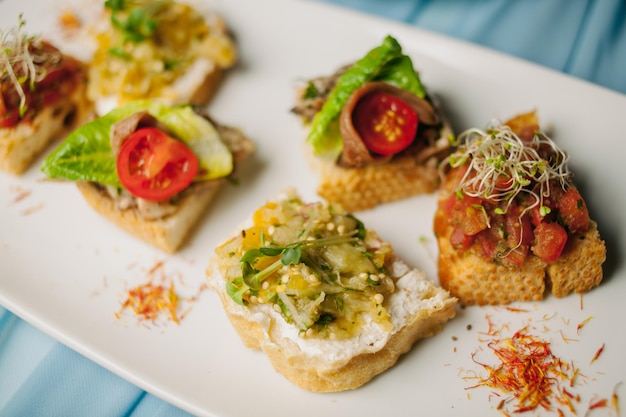 cold snacks, sandwiches with red fish, cucumbers, tomatoes on a white plate. wedding appetizers.