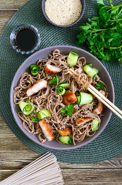 Cold soba with chicken, fresh cucumbers, sauce and sesame.
classic cold salad with buckwheat noodles. japanese food.
traditional asian cuisine. top view, flat lay.