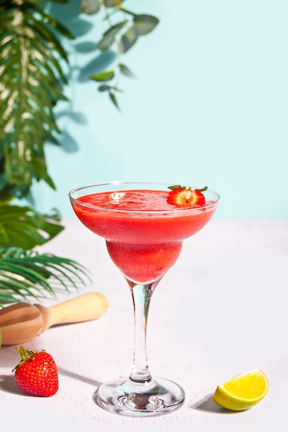 Cold strawberry margarita or daiquiri cocktail with lime and rum.