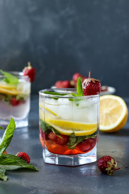 Bevanda fredda di mojito della fragola con la fragola, le fette del limone e la menta, foto verticale