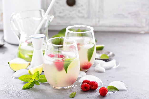 Cold summer cocktail with limes and raspberry