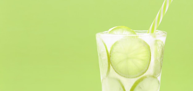 Cold summer drink with lime slices frozen in ice glass