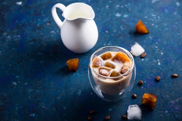 Cold summer refreshing drink with coffee ice and milk on a blue table