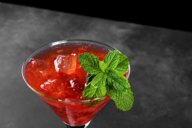 Cold summer strawberry cocktail mojito margarita daiquiri in a martini glass on dark background close up