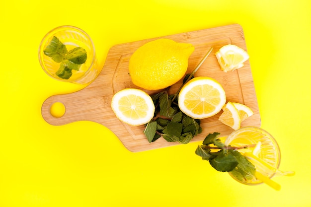 Limonata fredda e gustosa a base di limoni biologici e freschi su sfondo giallo