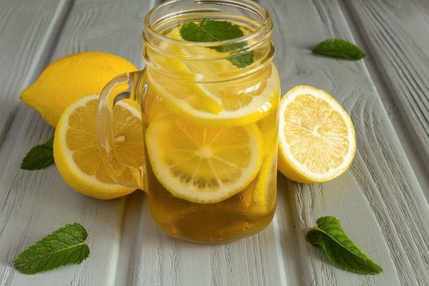 Холодный чай с лимоном в стакане на сером фоне