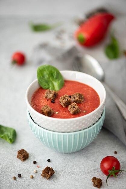 Cold tomato soup gazpacho with spinach and rye croutons in small bowls