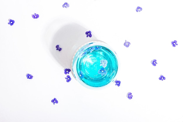 Cold tonic water and blue forget me not flowers on stand isolated on a white background