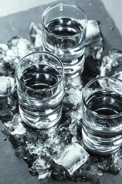 cold vodka in shot glasses on black.