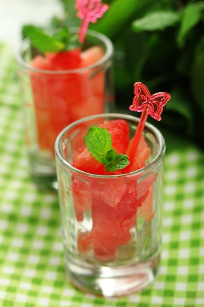 Cold watermelon pieces in glasses on wooden table background