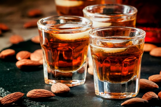 Cold whiskey with ice in a glass and a snack almonds selective focus