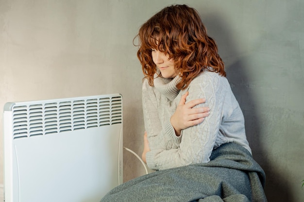 cold winter in the apartment a girl warms her hands near the heater battery heating season energy