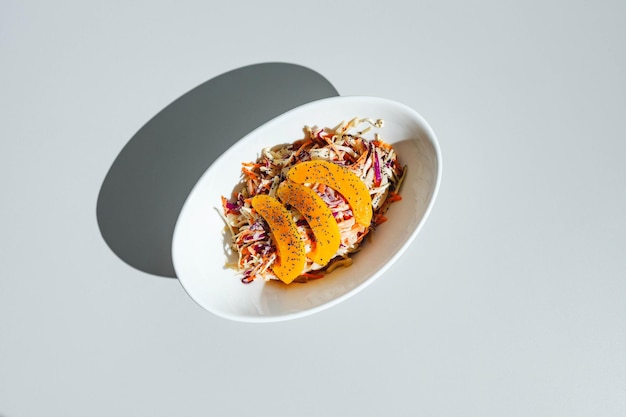 Cole slow salad with mango and poppy seeds on light background Hard light deep shadow