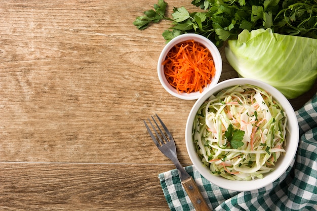 Coleslaw salad in white bowl on wooden table  