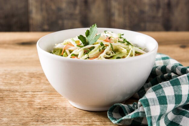 Coleslaw salad in white bowl on wooden table