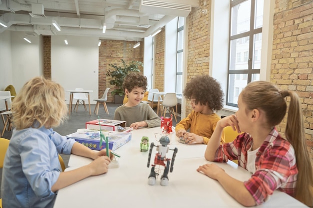 Collaboration clever diverse kids sitting at the table examining technical toys full of details