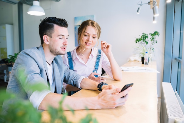 Photo colleague looking at smartphone in office