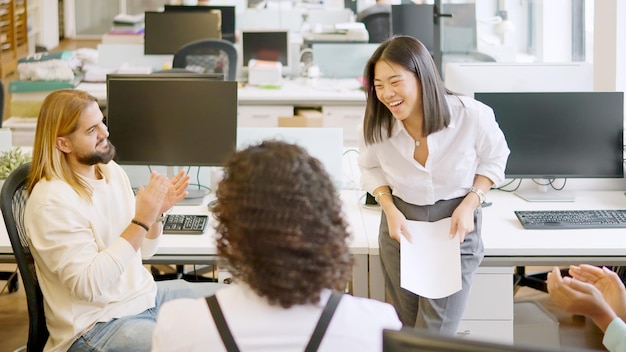 Colleagues applaud a businesswoman after a presentation in a meeting