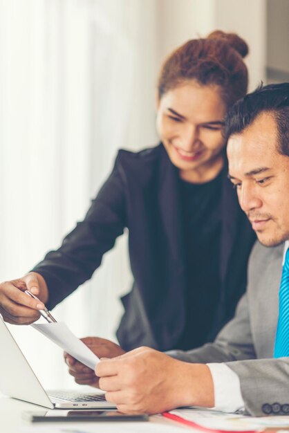 Colleagues discussing over laptop while sitting in office
